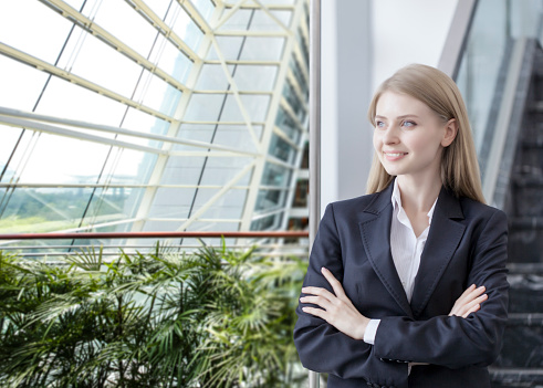 Smiling thoughtful businesswoman looking through window