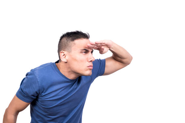 Studio portrait of man shielding his eyes from the light with his hand searching something