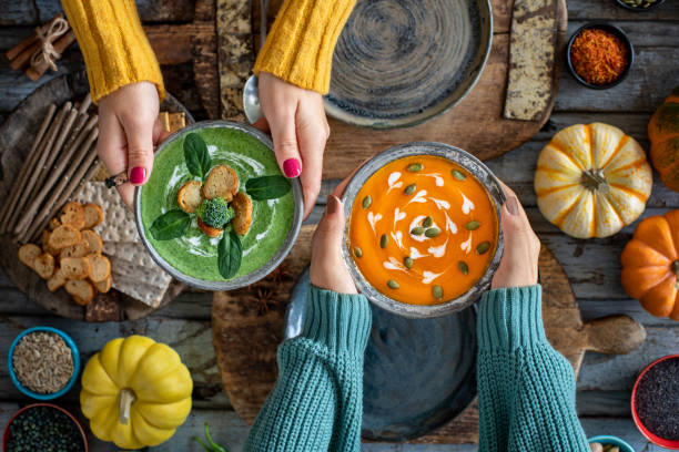 Two women drinking their vegetable soups. Detox soups, suitable for vegans and vegetarians squash soup stock pictures, royalty-free photos & images