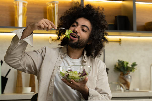 istock Egyptian man enjoys eating salad at table in modern kitchen 1368746079