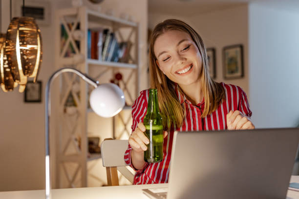 istock Young woman drinking beer while enjoying in a virtual party 1368748376