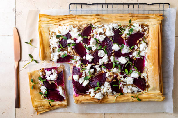 rote bete und feta filo pizza. rübentarte mit feta, karamellisierten zwiebeln, pinienkernen, sonnenblumen-mikrogemüse und phylloteig. herzhaftes vegetarisches gemüse backen. - filo pastry stock-fotos und bilder