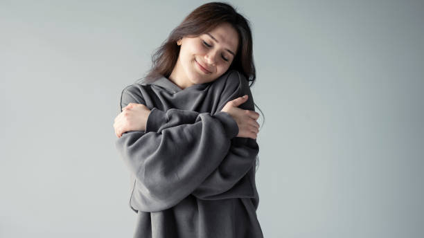 Hugging oneself happy and positive, smiling confident stock photo