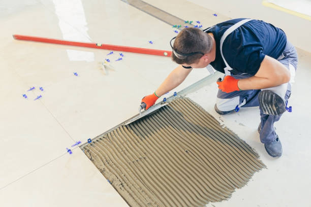 A male construction worker installs a large ceramic tile A male construction worker installs a large ceramic tile tiled floor stock pictures, royalty-free photos & images