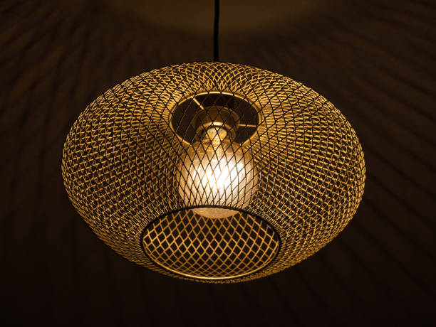 istock Ceiling light with golden metal grid and illuminated bulb. At night, black background 1368760153