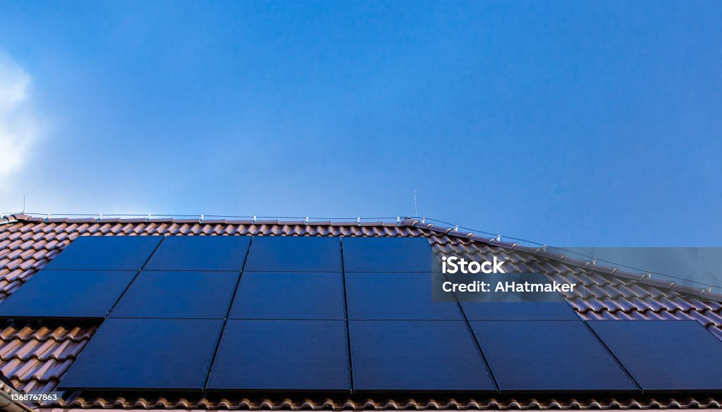 Modern full black solar panels on the roof of a house. Modern full black solar panels on the brown ceramic tiles roof of a house. Solar Panel Stock Photo