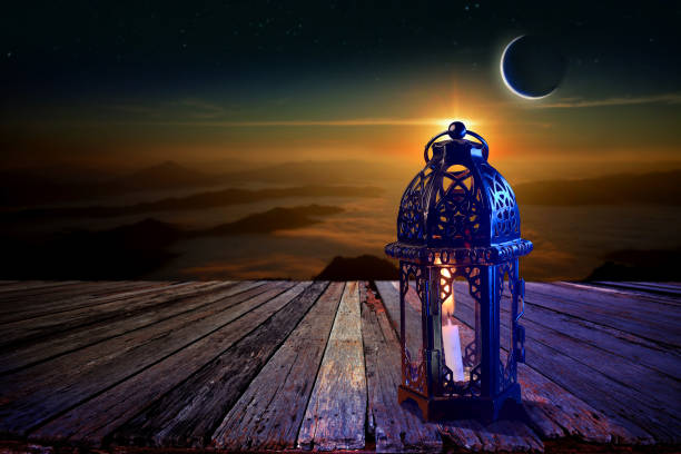 istock Arabian lanterns decorate an old wooden table with sky and crescent moon behind Ramadan Kareem background. 1368774468