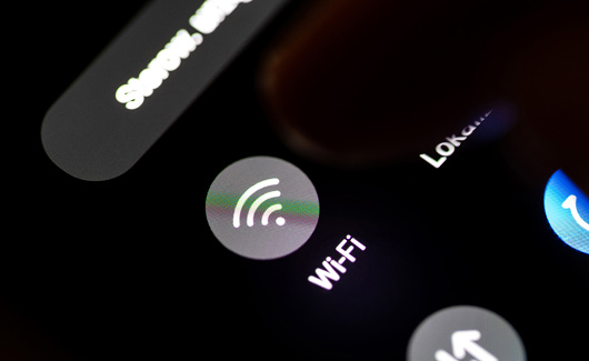 Finger turning on the WiFi module on a smartphone, mobile phone display, touch screen detail, closeup, macro, in the dark. Wifi wireless network internet access simple abstract concept, one person
