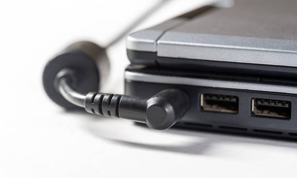 Plugging in a laptop power supply adapter, charger cable plug, object detail, closeup. Electricity, electrical power consumption and battery charging, recharging the battery concept, electrical device