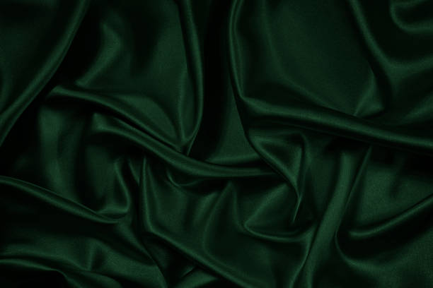 istock Green background. Folds on shiny fabric surface. Beautiful dark background 1368775978