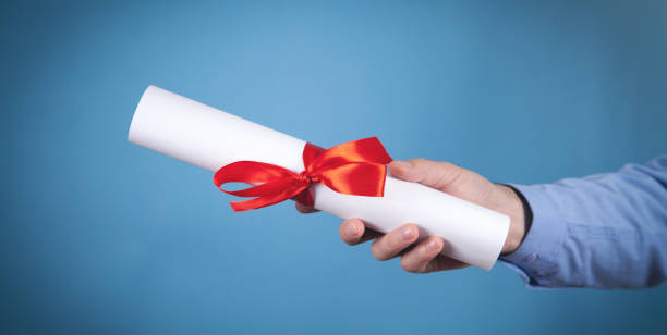istock Male hand holding diploma with a red ribbon. 1368777958