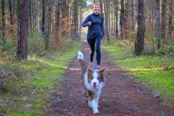 istock Smiling woman jogging outdoors with her dog 1368779237