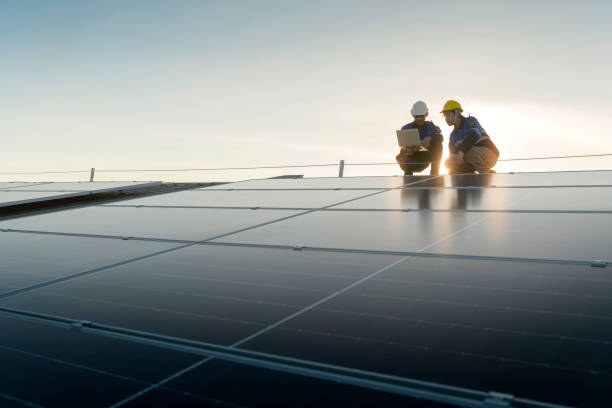 Specialist technician professional engineer with laptop and tablet maintenance checking installing solar roof panel on the factory rooftop under sunlight. Engineers team survey check solar panel roof. técnico especialista ingeniero profesional con control de mantenimiento de computadoras portátiles y tabletas instalando paneles solares en el techo de la fábrica bajo la luz solar. la encuesta del equipo de ingenieros verifica el techo del panel solar.
