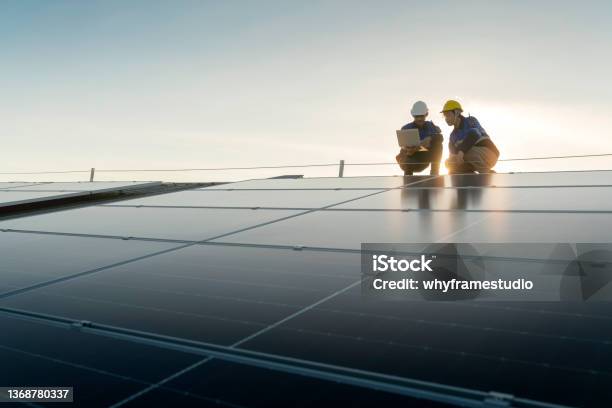Specialist Technician Professional Engineer With Laptop And Tablet Maintenance Checking Installing Solar Roof Panel On The Factory Rooftop Under Sunlight Engineers Team Survey Check Solar Panel Roof Stock Photo - Download Image Now