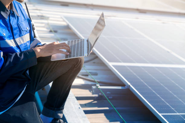 technicien spécialisé ingénieur professionnel avec maintenance d’ordinateur portable et de tablette vérifiant l’installation de panneaux de toit solaires sur le toit de l’usine sous la lumière du soleil. les ingénieurs tenant des tablettes vér - solar panel engineer solar power station women photos et images de collection