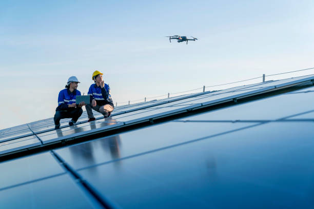 technicien spécialisé ingénieur professionnelcontrôle drone vérifiant la vue de dessus de l’installation du panneau de toit solaire sur le toit de l’usine sous la lumière du soleil. les ingénieurs tenant des tablettes vérifient le toit solaire. - drone photos et images de collection