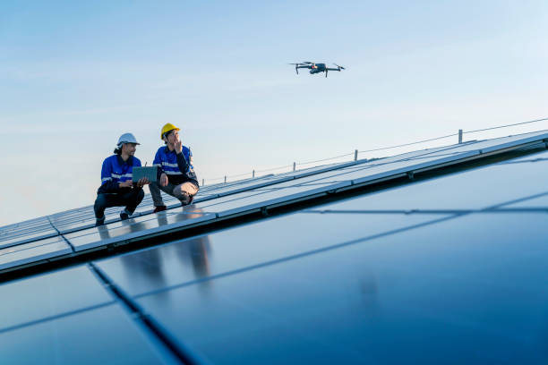 specialist technician professional engineercontrol drone checking top view of installing solar roof panel on the factory rooftop under sunlight. engineers holding tablet check solar roof. - service engineer fotos imagens e fotografias de stock