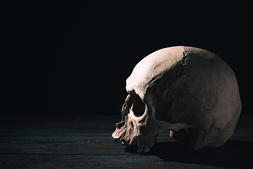 Old human skull close up against black background.