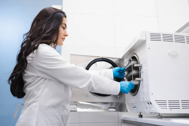 la asistente médica femenina está sacando bolsillos con instrumentos dentales esterilizados del autoclave - laboratory assistant healthcare and medicine chemistry fotografías e imágenes de stock