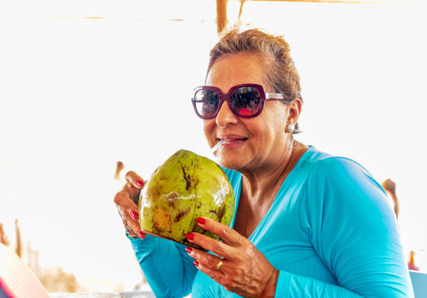 istock Attractive senior Hispanic woman drinking Coconut water 1368787986