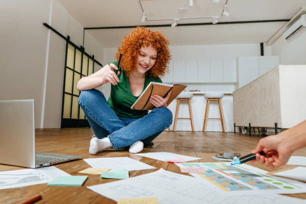 istock Two young women discussing new project sitting on the floor 1368789673