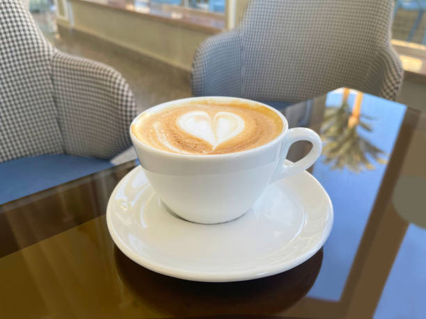 istock Cappuccino in a white cup decorated with a heart on top on a glass table 1368790996