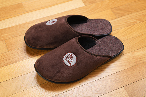 Brown home slippers on the parquet floor.Clear warm domestic sandal or sneakers. Bed shoes accessory footwear.