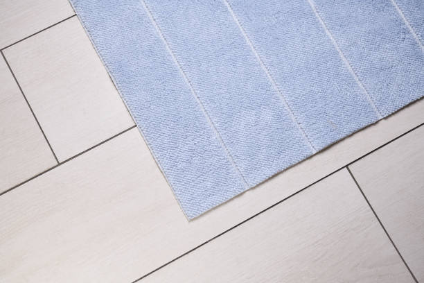 istock Blue rug on white ceramic tile with wood texture. View from above. 1368791338