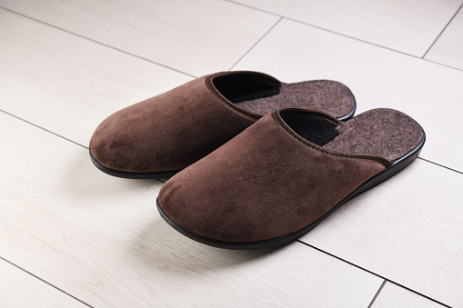 Brown home slippers on the ceramic floor.Clear warm domestic sandals or sneakers. Bed shoes accessory footwear.