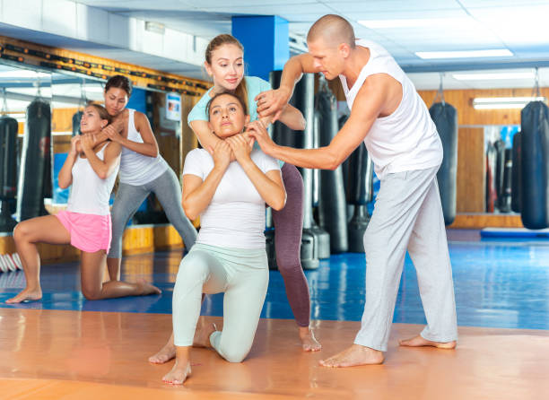 istock Self-defense instructor teaching women to perform guillotine choke 1368796096