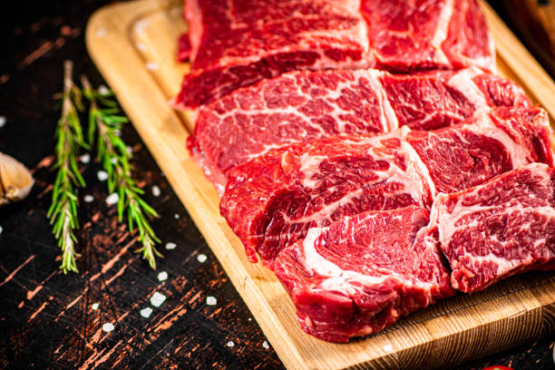 istock Raw beef on a wooden cutting board with rosemary. 1368799325