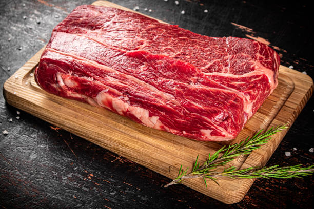 istock Raw beef on a wooden cutting board with rosemary. 1368801893