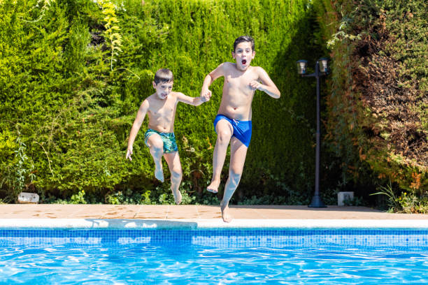 istock Two kids jumping into a pool in a sunny day 1368802169