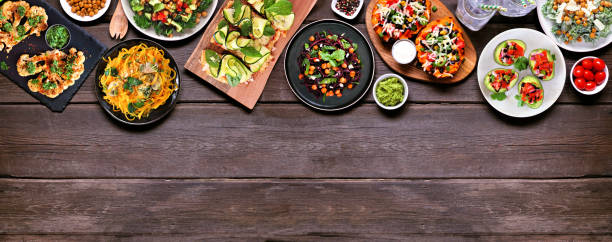 istock Healthy plant based, low carb diet top border. Overhead view on a dark wood banner background. 1368802475