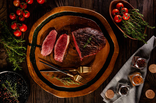 Resin wooden cutting board Grilled sliced cap rump steak with golden forks and spices on wooden cutting board (Brazilian picanha) - Top view. barbecue beef stock pictures, royalty-free photos & images