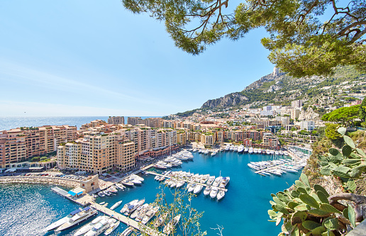 Panoramic image of Port Fontvieille - Monaco, top view from Monaco Ville, azur water, sun reflections on the water, harbour at sunny day, luxury apartments, a lot of yachts and boats, mountain. High quality photo