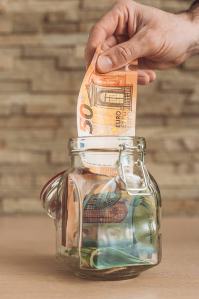 istock A man puts saved Euro banknotes in a glass jar 1368809780