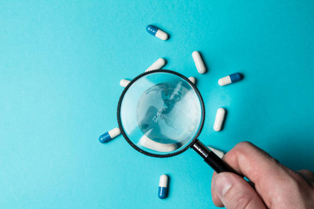 istock Globe and pills under magnifying glass on turquoise background. Under the supervision of healthcare. Monitoring the health of the planet Earth. People's health is under the control of doctors. Closeup 1368811049