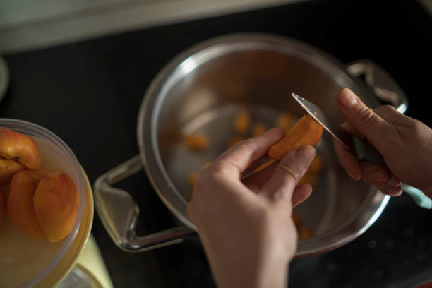 istock Female hands cutting fresh sweet peaches to make peach jam. 1368812559