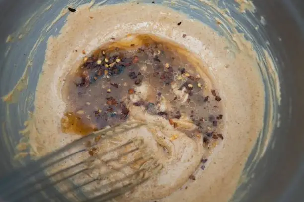 Mixing peanut butter with various ingredients in a large bowl to make Thai peanut sauce.