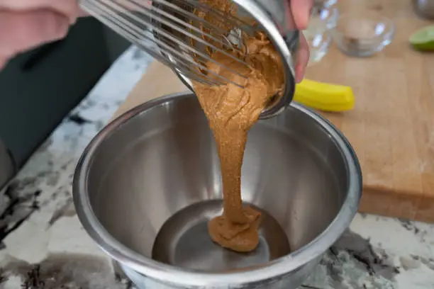 Pouring peanut butter into larger bowl