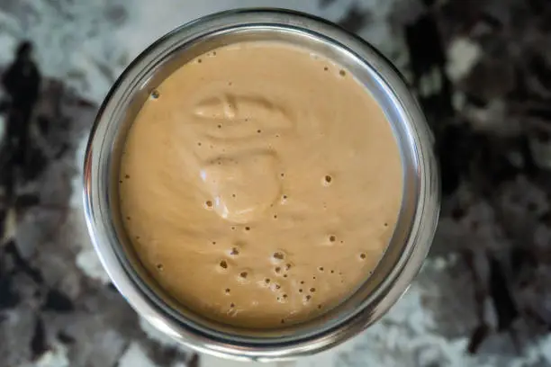 Detailed overhead view of Thai peanut sauce in a small metal bowl w/ no shadow.