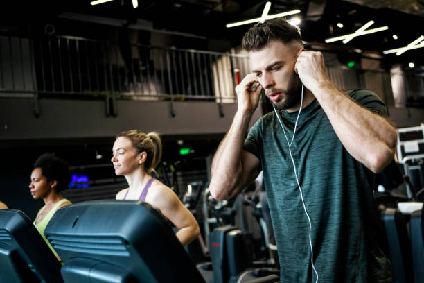 istock Young man running on a treadmill wearing headphones 1368818648