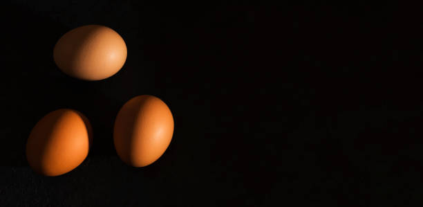 istock Natural home product banner. Fresh brown eggs with hard shadows on a dark background. Minimalism. Top view. copy space. 1368820178