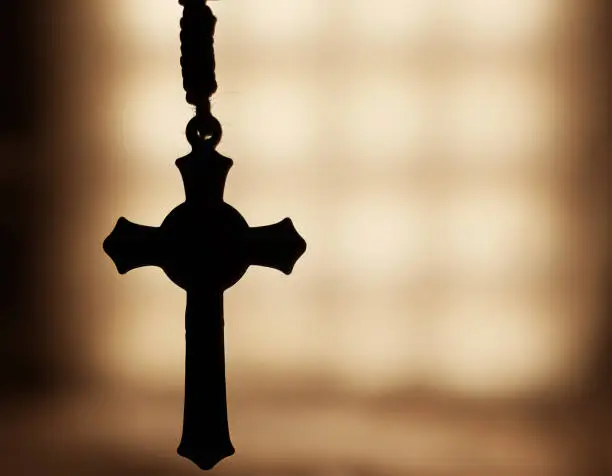 Photo of Close-up picture of a silhouette of a Rosary with a blurry background