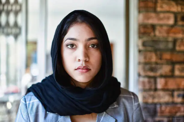 Photo of Beautiful young Muslim woman wearing hijab looks seriously at the camera
