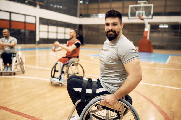 portrait d’un heureux basketteur en fauteuil roulant pendant l’entraînement sportif sur le terrain. - sports en fauteuil roulant photos et images de collection