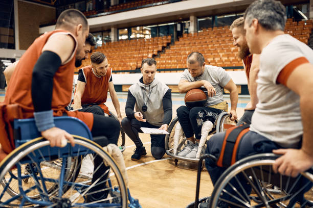 휠체어 농구 코치와 코트에서 경기 전략을 거닐는 장애인 선수들. - 농구 팀 스포츠 뉴스 사진 이미지