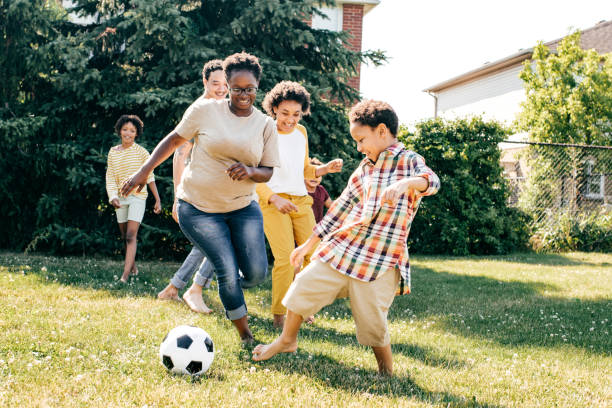 Multi-ethnic family playing soccer outdoors stock photo