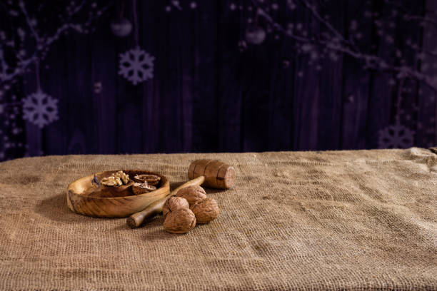 Nuts, a typical Christmas nut, on a wooden plate with a mallet to hit them, on a dark background with Christmas motifs.